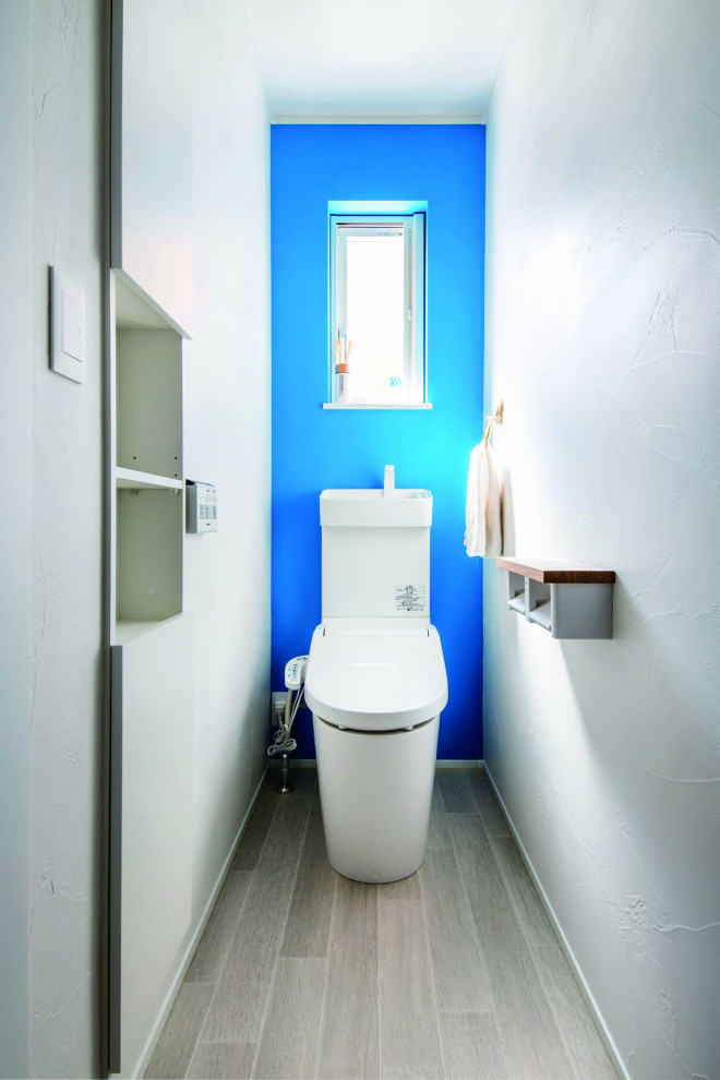Diseño de aseo blanco de tamaño medio con sanitario de una pieza, paredes azules, suelo de madera pintada, suelo gris, papel pintado y papel pintado
