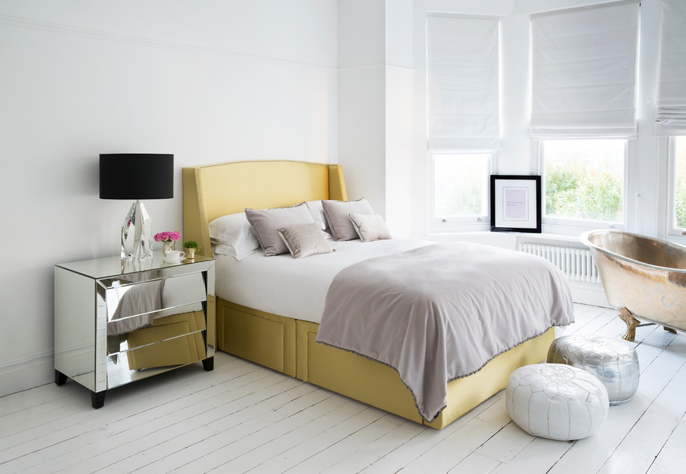 This is an example of a contemporary bedroom in London with white walls and painted wood floors.