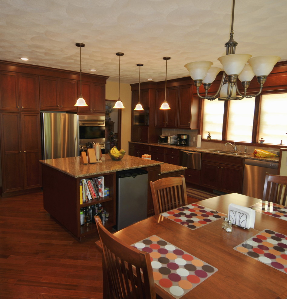 Eat-in kitchen - large transitional medium tone wood floor eat-in kitchen idea in New York with recessed-panel cabinets, an island, an undermount sink, dark wood cabinets, quartz countertops, beige backsplash, ceramic backsplash and stainless steel appliances