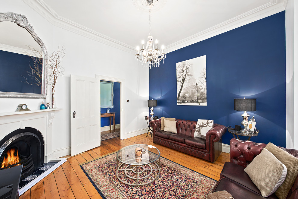 Inspiration for a traditional enclosed living room in Melbourne with blue walls, light hardwood floors and a corner fireplace.