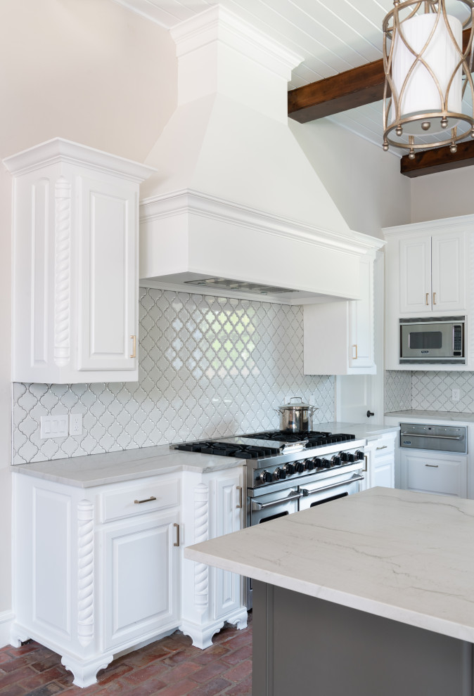 This is an example of a large transitional u-shaped eat-in kitchen in Dallas with raised-panel cabinets, white cabinets, quartzite benchtops, white splashback, stainless steel appliances, brick floors and multiple islands.