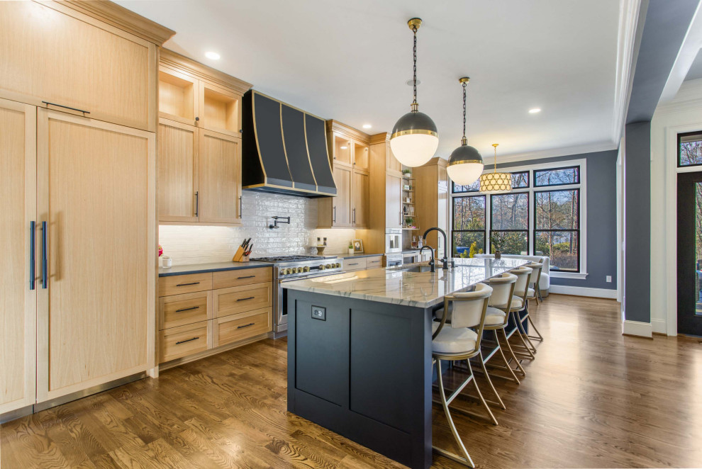 Example of a transitional galley medium tone wood floor and brown floor eat-in kitchen design with quartzite countertops, paneled appliances, an island, an undermount sink, shaker cabinets, medium tone wood cabinets, white backsplash, subway tile backsplash and gray countertops