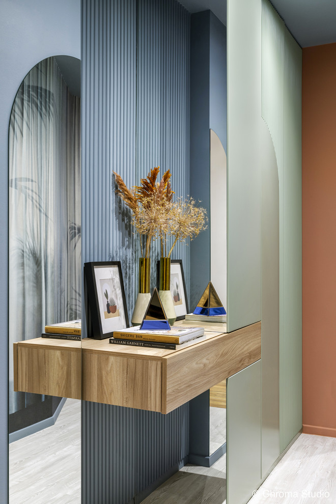 Photo of a mid-sized contemporary foyer in Milan with a single front door, blue walls, light hardwood floors, a white front door, white floor, recessed and wallpaper.