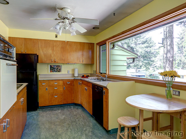Inspiration for a mid-sized midcentury u-shaped eat-in kitchen in Portland with a drop-in sink, flat-panel cabinets, medium wood cabinets, laminate benchtops, beige splashback, black appliances and linoleum floors.