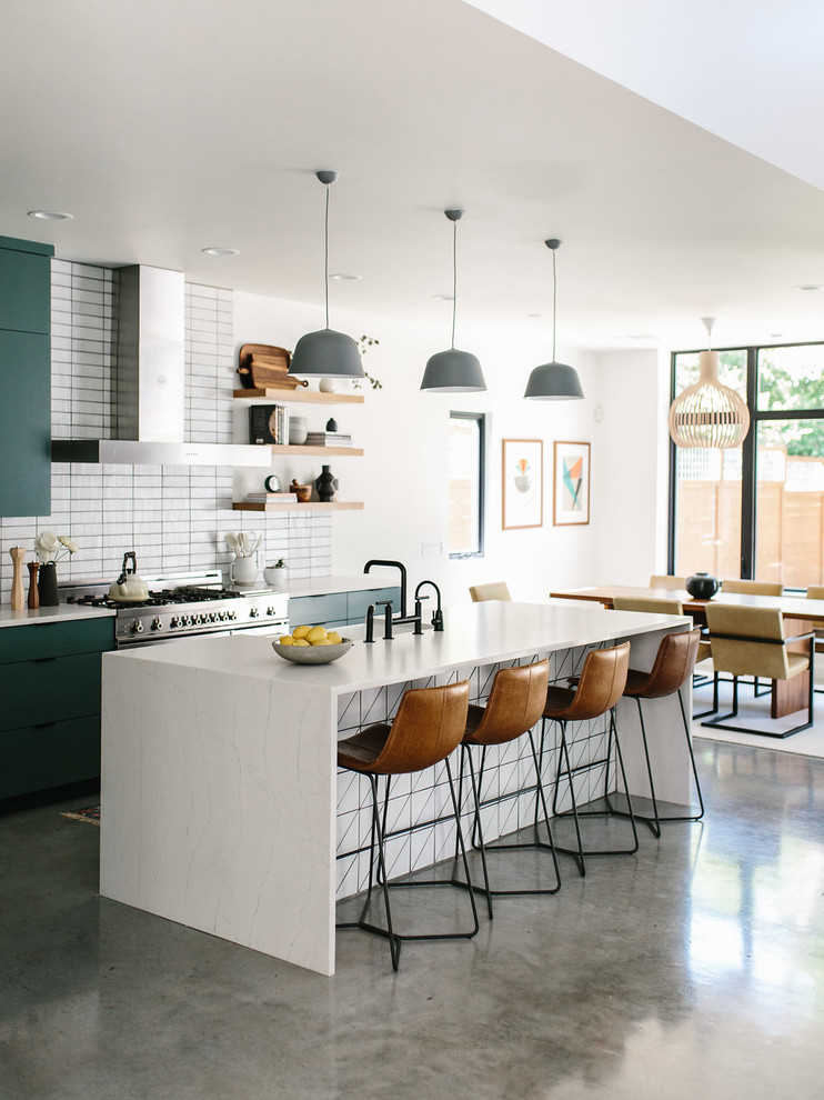 Photo of a mid-sized contemporary l-shaped eat-in kitchen in Austin with a farmhouse sink, flat-panel cabinets, green cabinets, quartzite benchtops, white splashback, brick splashback, stainless steel appliances, concrete floors, with island, grey floor and white benchtop.