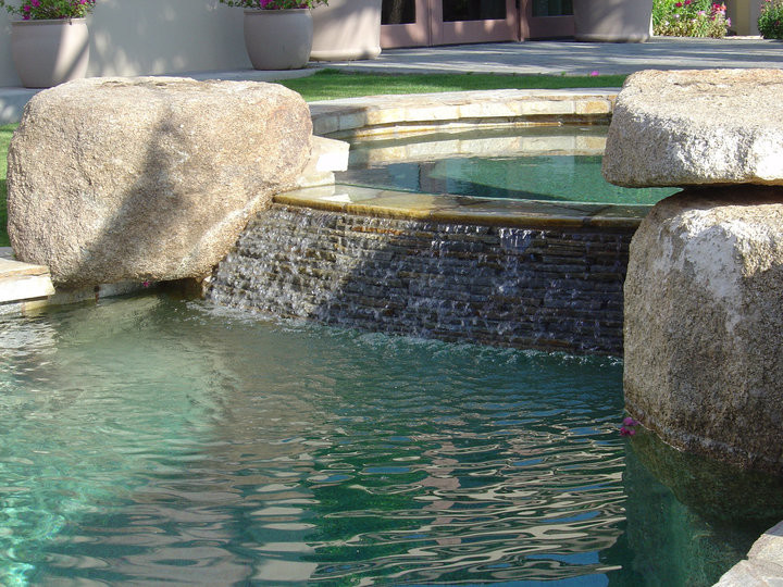 Small mediterranean backyard custom-shaped natural pool in Orange County with natural stone pavers and a hot tub.