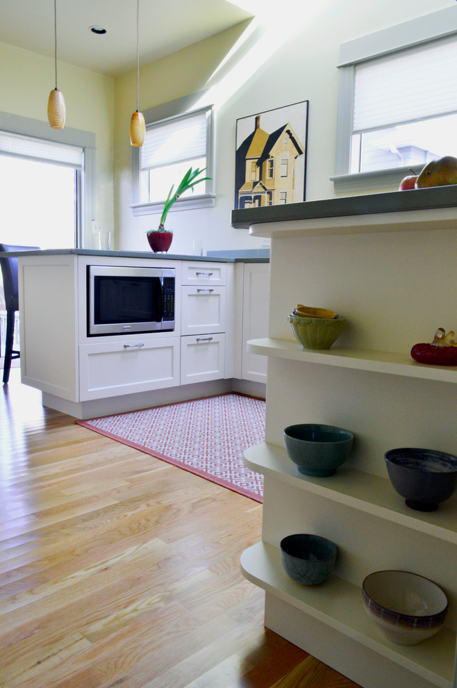 Inspiration for a mid-sized transitional u-shaped light wood floor and brown floor enclosed kitchen remodel in Seattle with an undermount sink, recessed-panel cabinets, white cabinets, quartz countertops, white backsplash, subway tile backsplash, stainless steel appliances and a peninsula