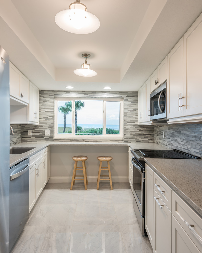 Example of a mid-sized transitional l-shaped porcelain tile and gray floor kitchen pantry design in Orlando with an undermount sink, shaker cabinets, white cabinets, quartz countertops, gray backsplash, mosaic tile backsplash, stainless steel appliances, no island and white countertops