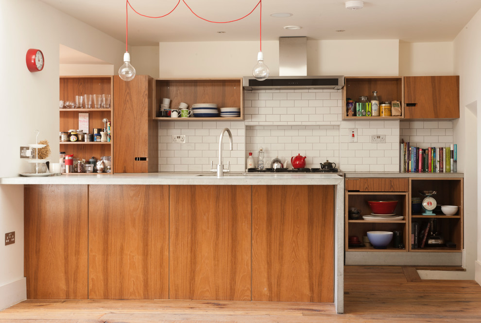 This is an example of a mid-sized midcentury galley open plan kitchen in Dublin with flat-panel cabinets, medium wood cabinets, concrete benchtops and with island.