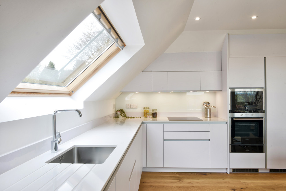 Küche in grau-weiß in L-Form mit Küchenrückwand in Weiß, hellem Holzboden und braunem Boden in Glasgow