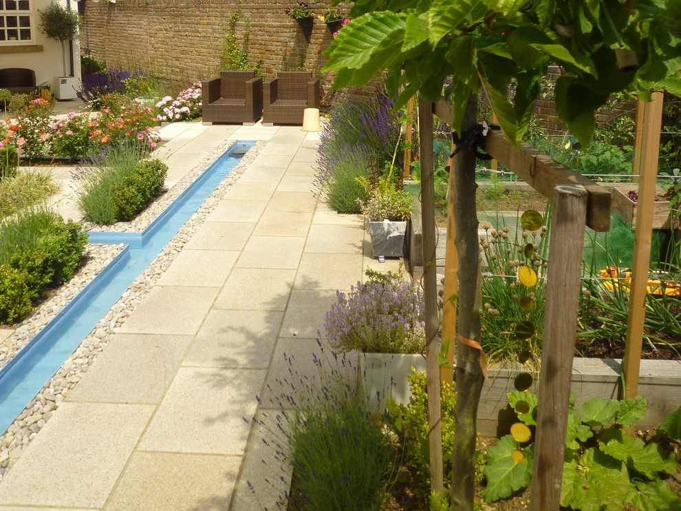 Design ideas for a mid-sized modern courtyard partial sun formal garden in Hertfordshire with natural stone pavers and a water feature.