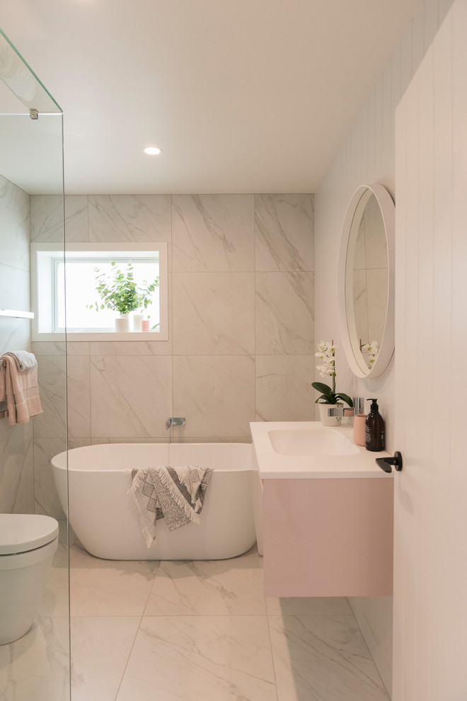 This is an example of a contemporary bathroom in Auckland with flat-panel cabinets, a freestanding tub, white tile, white walls, a console sink, an alcove shower, a one-piece toilet, ceramic tile, cement tiles, grey floor, a hinged shower door and white benchtops.