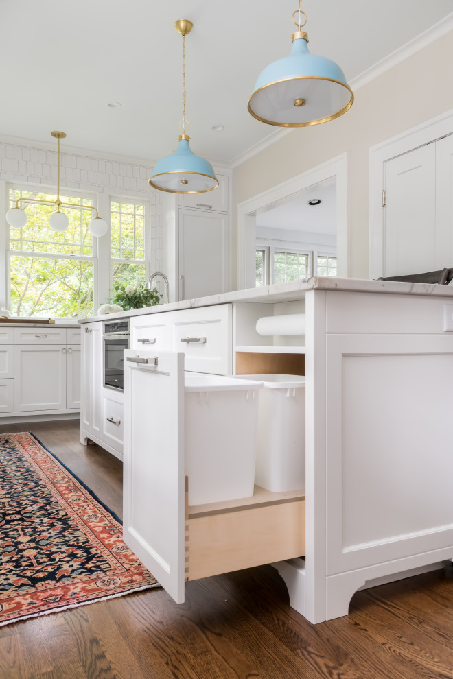 Photo of a large beach style galley eat-in kitchen in Atlanta with an undermount sink, shaker cabinets, white cabinets, quartzite benchtops, white splashback, marble splashback, panelled appliances, dark hardwood floors, with island, brown floor and white benchtop.