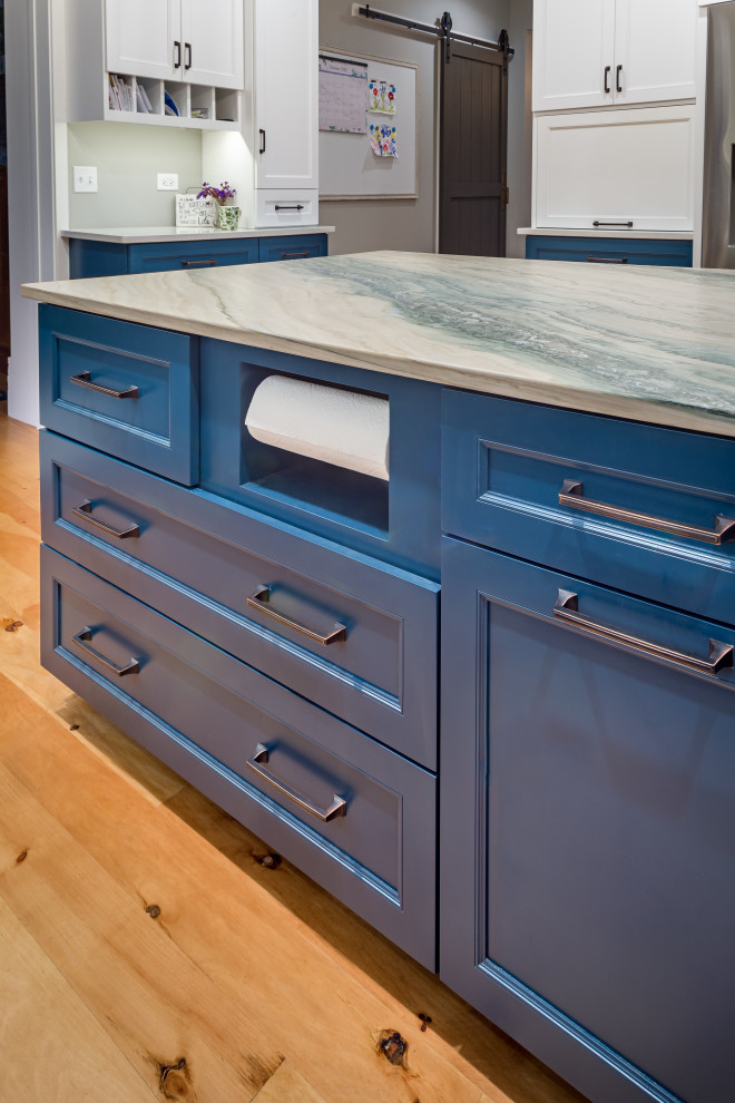 Mid-sized country l-shaped eat-in kitchen in Chicago with a farmhouse sink, recessed-panel cabinets, blue cabinets, quartzite benchtops, white splashback, ceramic splashback, stainless steel appliances, light hardwood floors, with island, multi-coloured floor and multi-coloured benchtop.