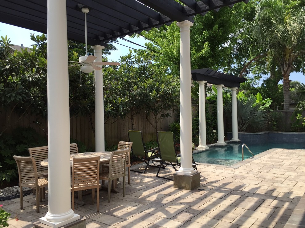 This is an example of a mid-sized traditional backyard patio in New Orleans with a water feature, natural stone pavers and a pergola.