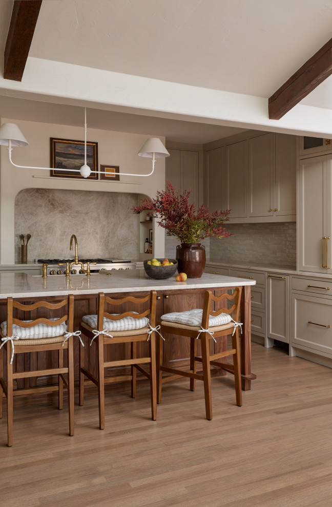 Design ideas for a transitional l-shaped kitchen in Dallas with a farmhouse sink, shaker cabinets, beige cabinets, beige splashback, stone slab splashback, stainless steel appliances, light hardwood floors, with island, beige floor, beige benchtop, exposed beam and vaulted.