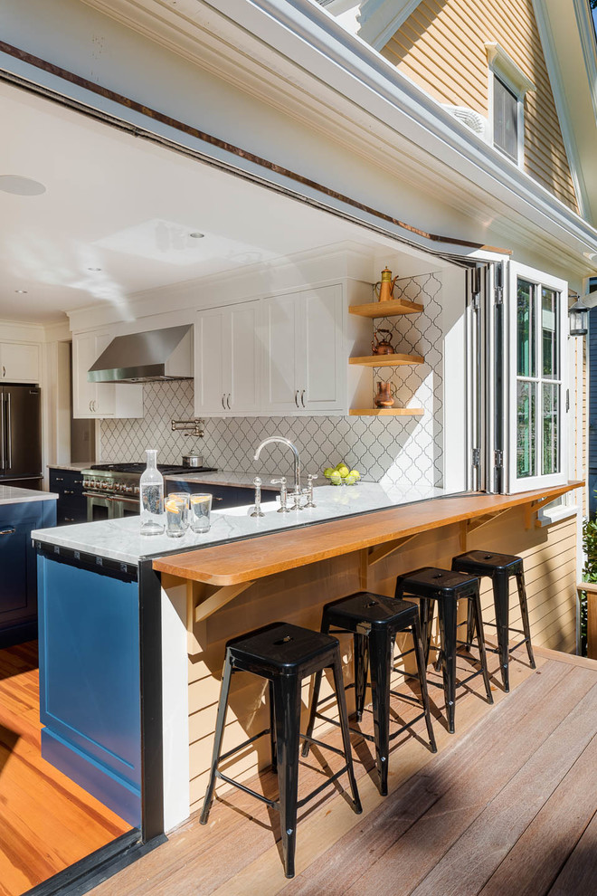 Inspiration for a mid-sized contemporary l-shaped eat-in kitchen in Boston with a farmhouse sink, recessed-panel cabinets, white cabinets, quartzite benchtops, white splashback, porcelain splashback, stainless steel appliances, medium hardwood floors, with island and brown floor.