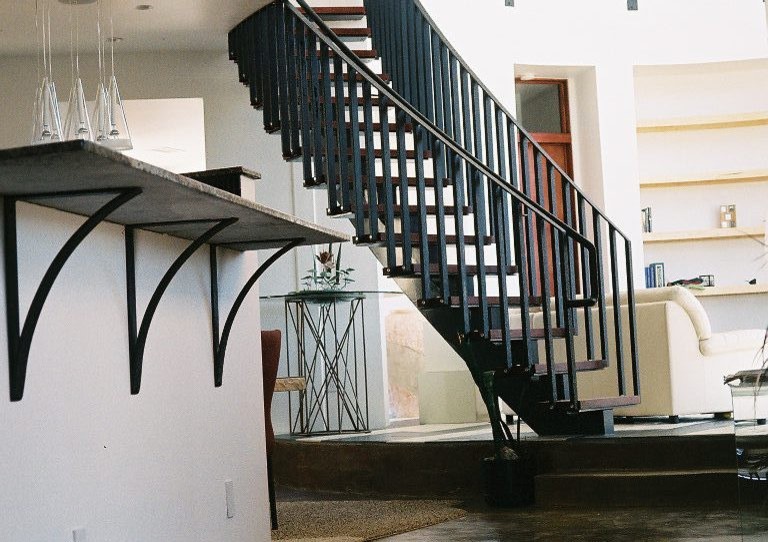 Modern wood curved staircase in Albuquerque with open risers and metal railing.