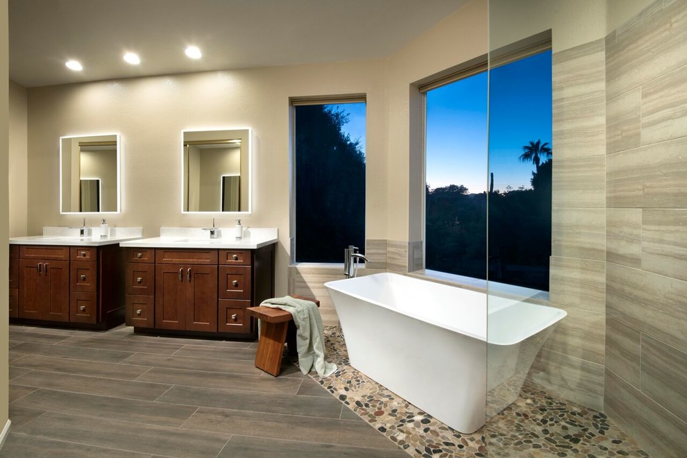 Transitional master beige tile and porcelain tile pebble tile floor freestanding bathtub photo in Phoenix with shaker cabinets, dark wood cabinets, beige walls and quartz countertops