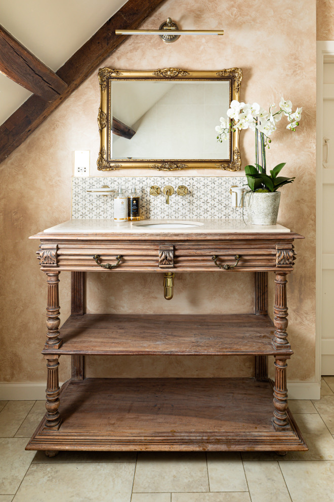 This is an example of a mid-sized traditional master bathroom in Gloucestershire with raised-panel cabinets, a freestanding tub, beige tile, beige walls, vinyl floors, marble benchtops, beige floor, pink benchtops, a freestanding vanity, exposed beam, medium wood cabinets, a two-piece toilet, mosaic tile, an integrated sink, a hinged shower door, a single vanity and a corner shower.