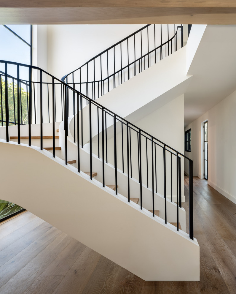 Design ideas for a large mediterranean wood curved staircase in Los Angeles with limestone risers and metal railing.
