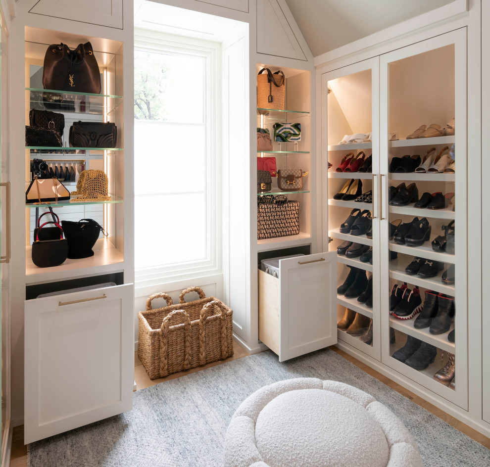 Photo of a large gender-neutral walk-in wardrobe in Dallas with shaker cabinets, white cabinets, light hardwood floors, brown floor and vaulted.