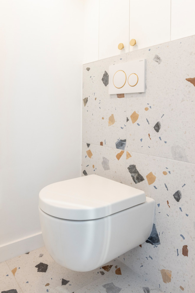 Idée de décoration pour un petit WC suspendu design avec des portes de placard blanches, un mur blanc, un sol en terrazzo, un plan de toilette en carrelage et meuble-lavabo encastré.