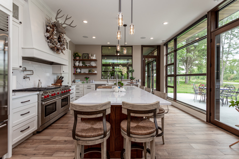 Design ideas for a mid-sized country kitchen in Other with with island, shaker cabinets, white cabinets, white splashback, stone slab splashback, stainless steel appliances, medium hardwood floors and white benchtop.