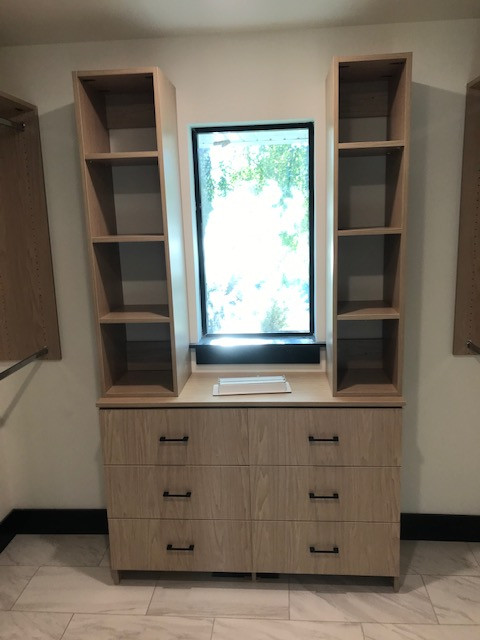 Mid-sized mountain style gender-neutral porcelain tile and white floor walk-in closet photo with recessed-panel cabinets and light wood cabinets