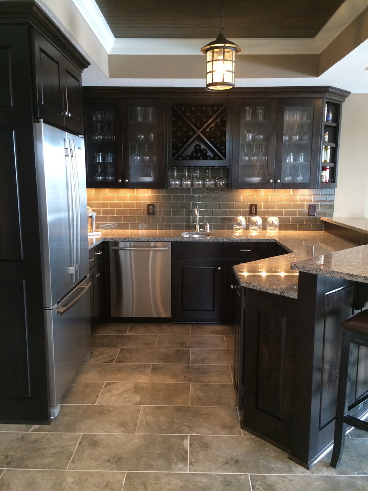 Enclosed kitchen - small modern galley ceramic tile enclosed kitchen idea with an undermount sink, flat-panel cabinets, dark wood cabinets, granite countertops, gray backsplash, glass tile backsplash and stainless steel appliances