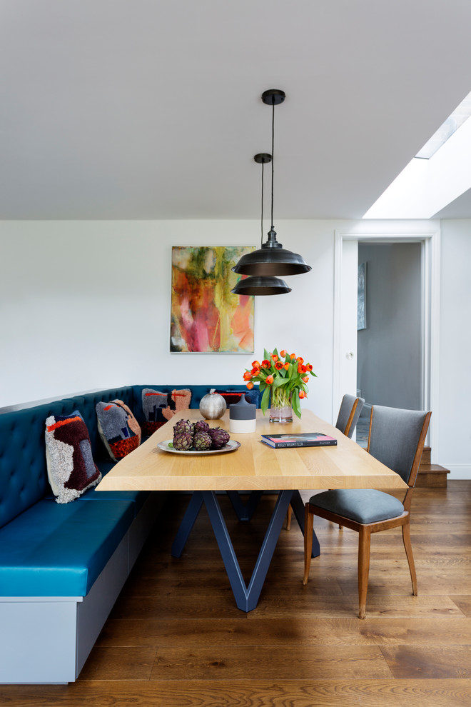 This is an example of a contemporary dining room in London with white walls, medium hardwood floors and brown floor.