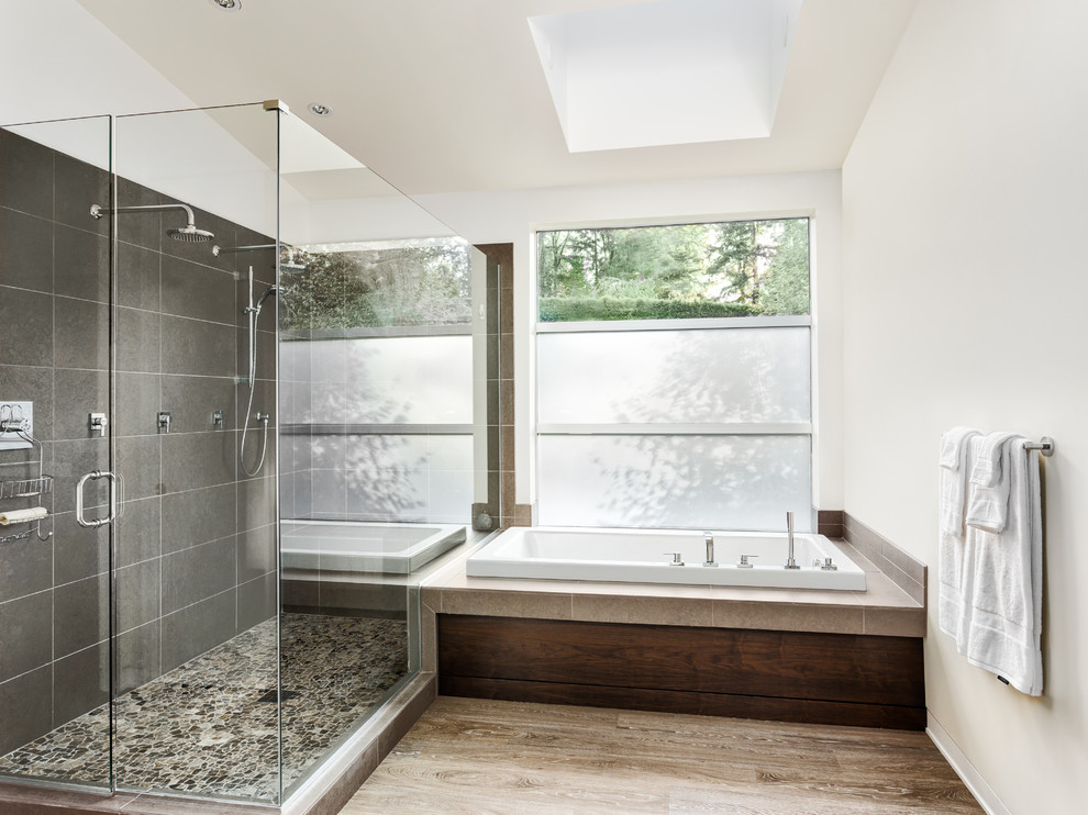 Photo of a large contemporary ensuite bathroom in Los Angeles with raised-panel cabinets, light wood cabinets, a corner bath, a double shower, a one-piece toilet, beige tiles, stone tiles, white walls, a built-in sink and marble worktops.