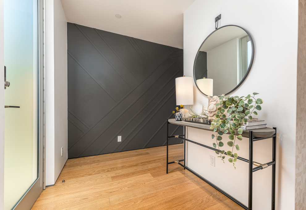 This is an example of a medium sized contemporary foyer in Los Angeles with black walls, medium hardwood flooring, a single front door, a glass front door and wood walls.