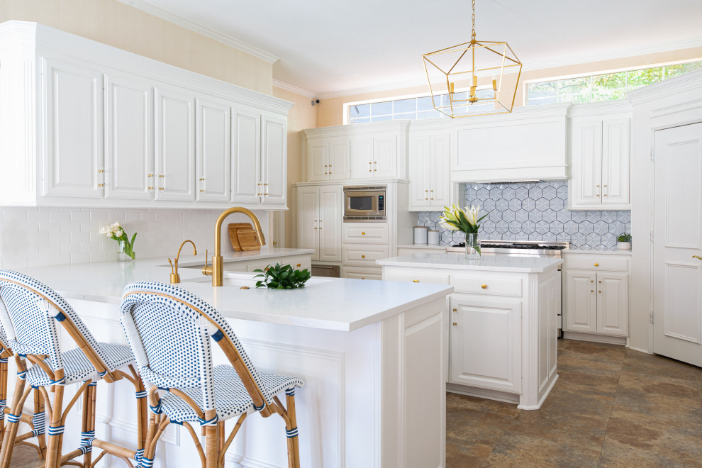 Inspiration for a mid-sized beach style kitchen in Dallas with an undermount sink, raised-panel cabinets, white cabinets, quartz benchtops, blue splashback, ceramic splashback, white appliances, multiple islands and white benchtop.