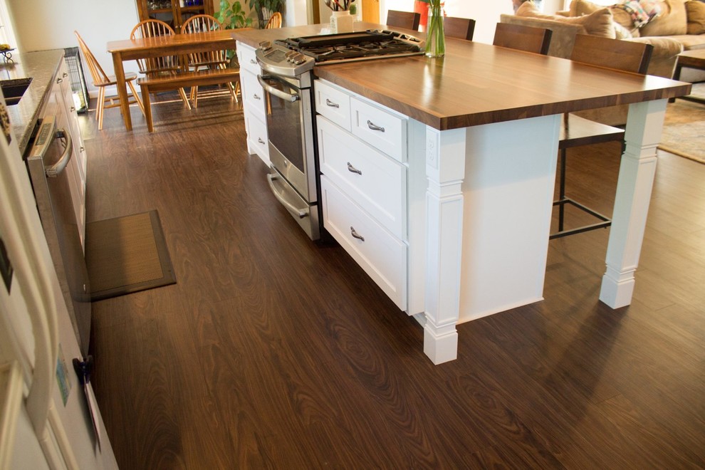 Inspiration for a mid-sized transitional galley dark wood floor and brown floor open concept kitchen remodel with an undermount sink, shaker cabinets, white cabinets, wood countertops, white backsplash, porcelain backsplash, white appliances and an island