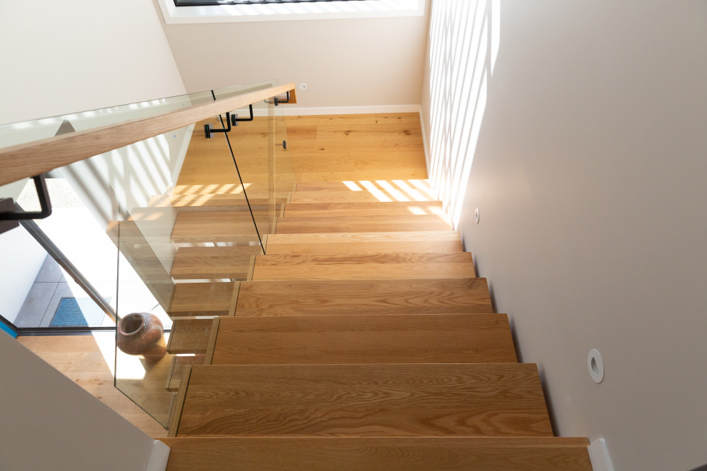 Inspiration for a medium sized modern wood floating mixed railing staircase in Auckland with open risers.