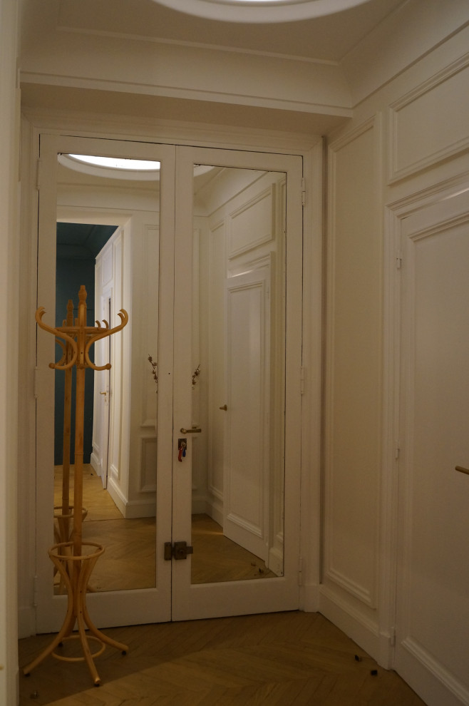 Ejemplo de puerta principal clásica grande con paredes beige, suelo de madera clara, puerta doble, puerta blanca, suelo marrón, bandeja y boiserie