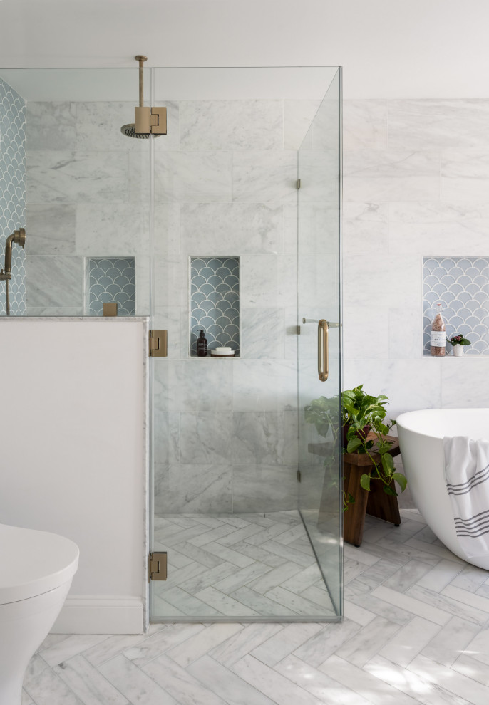 Inredning av ett stort vit vitt en-suite badrum, med blå skåp, ett fristående badkar, en kantlös dusch, en bidé, marmorkakel, grå väggar, marmorgolv, ett undermonterad handfat, bänkskiva i kvarts, vitt golv och dusch med gångjärnsdörr