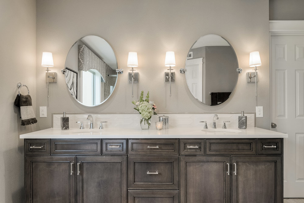 Inspiration for a mid-sized transitional master bathroom with recessed-panel cabinets, dark wood cabinets, a freestanding tub, an alcove shower, a one-piece toilet, gray tile, porcelain tile, grey walls, ceramic floors, engineered quartz benchtops, beige floor and a sliding shower screen.