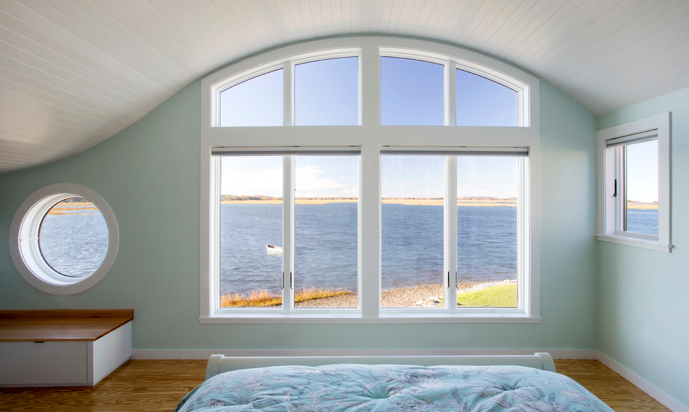 This is an example of a mid-sized beach style master bedroom in Boston with blue walls and light hardwood floors.