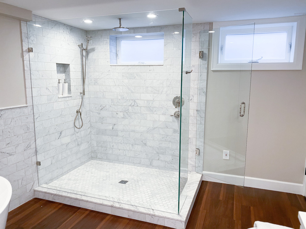 Photo of a large arts and crafts master bathroom in Seattle with shaker cabinets, white cabinets, a freestanding tub, an open shower, a two-piece toilet, white tile, marble, beige walls, vinyl floors, an undermount sink, engineered quartz benchtops, brown floor, a hinged shower door, pink benchtops, a double vanity and a built-in vanity.