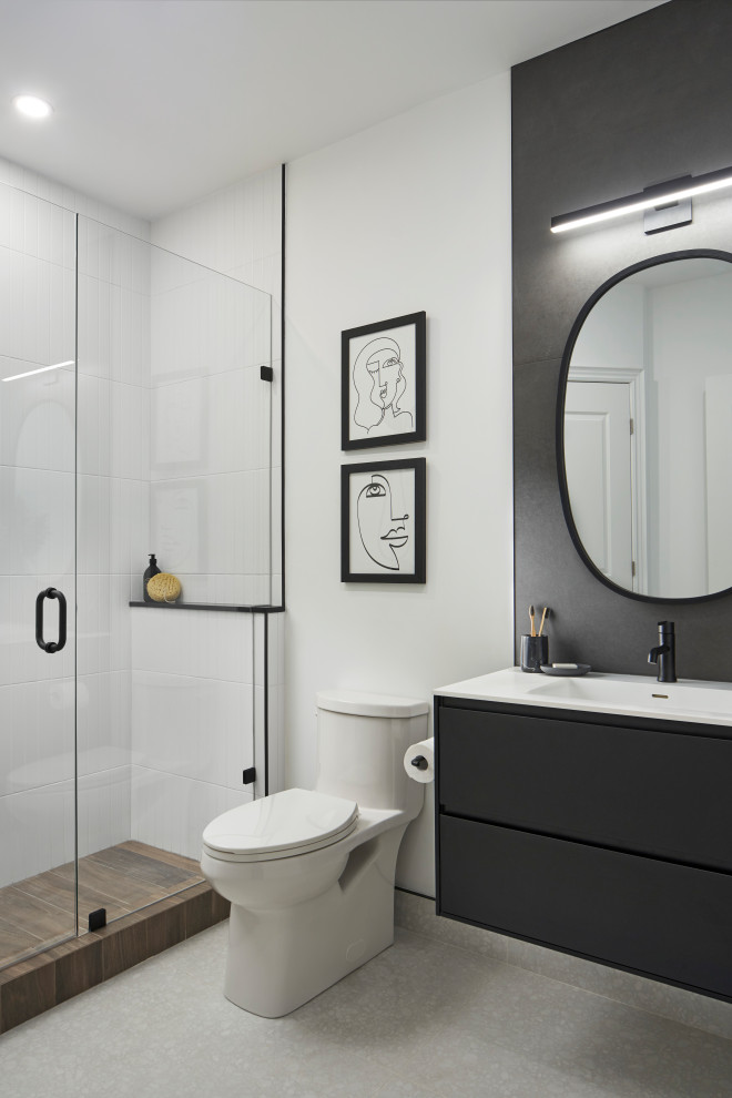 На фото: ванная комната среднего размера со стиральной машиной в стиле модернизм с плоскими фасадами, черными фасадами, душем в нише, унитазом-моноблоком, керамогранитной плиткой, белыми стенами, полом из керамогранита, душевой кабиной, монолитной раковиной, столешницей из искусственного кварца, белым полом, душем с распашными дверями, белой столешницей, тумбой под одну раковину, подвесной тумбой и белой плиткой