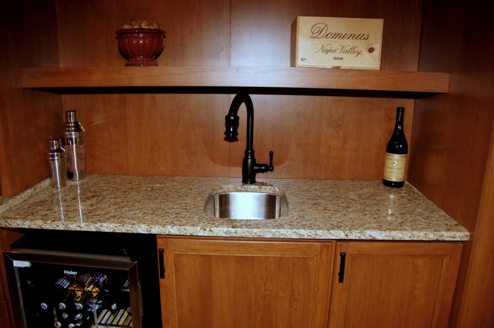 Photo of a mediterranean wet bar in Indianapolis with an undermount sink, recessed-panel cabinets, brown cabinets, granite benchtops, concrete floors, multi-coloured floor and multi-coloured benchtop.