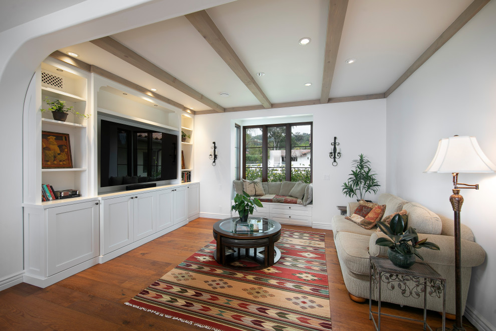 Inspiration for a mid-sized mediterranean open concept family room in Santa Barbara with white walls, medium hardwood floors, no fireplace, brown floor and a wall-mounted tv.