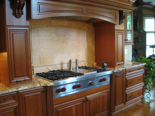 Example of a large transitional u-shaped medium tone wood floor and brown floor open concept kitchen design in Raleigh with raised-panel cabinets, medium tone wood cabinets, granite countertops, beige backsplash, ceramic backsplash, stainless steel appliances, an undermount sink, an island and brown countertops