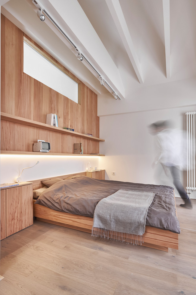 This is an example of a contemporary bedroom in Moscow with white walls, light hardwood floors and beige floor.