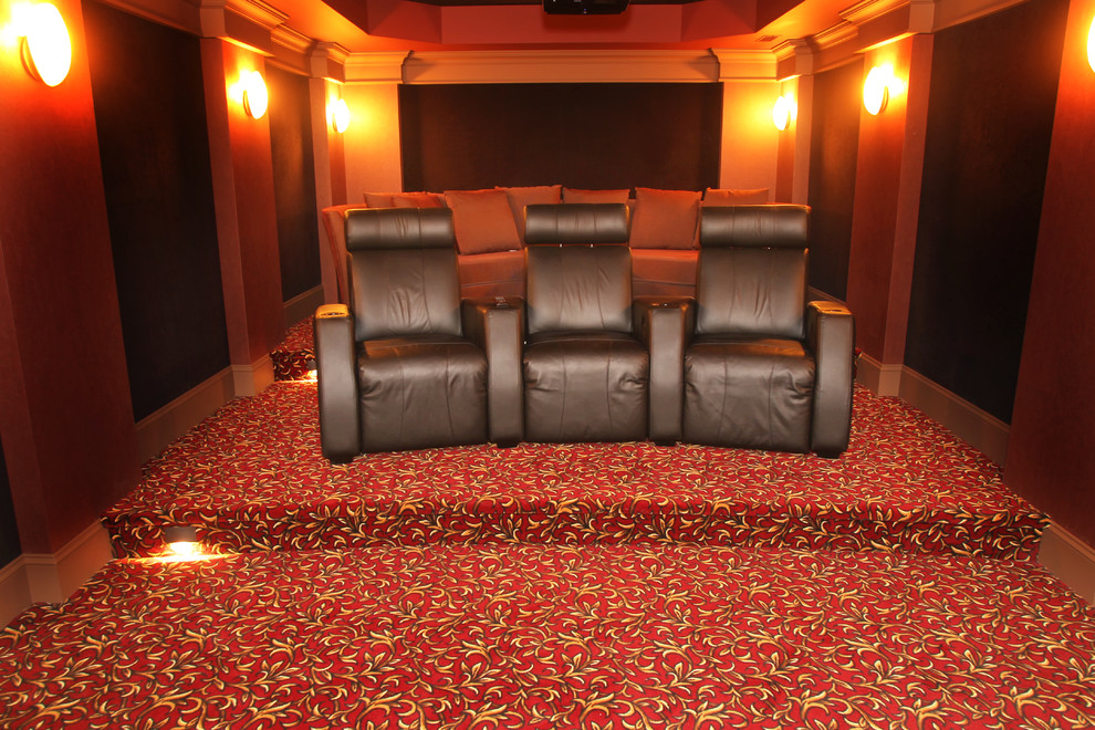 This is an example of a small enclosed home theatre in Vancouver with red walls, carpet and a projector screen.