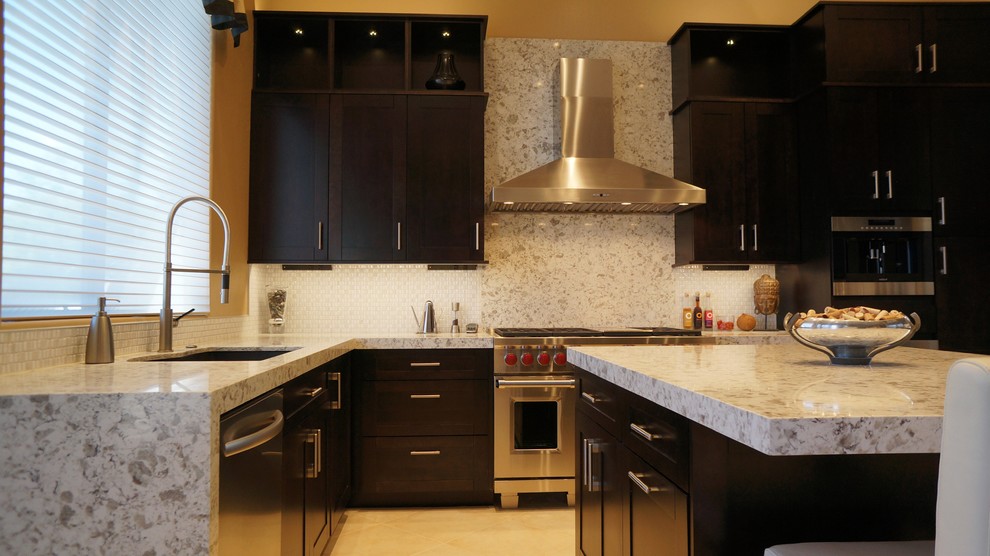 Transitional l-shaped porcelain tile and beige floor kitchen photo in Phoenix with an undermount sink, recessed-panel cabinets, dark wood cabinets, quartz countertops, white backsplash, ceramic backsplash, stainless steel appliances and an island