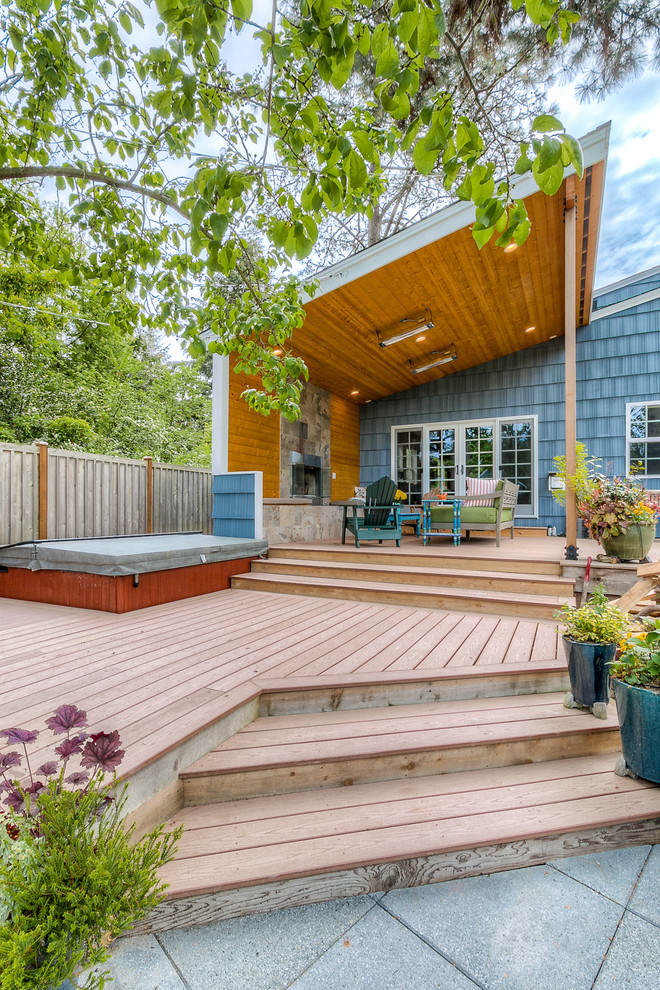 Large arts and crafts backyard deck in Seattle with a fire feature and a roof extension.