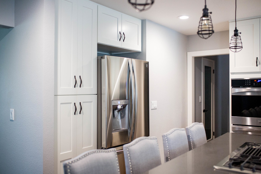 Eat-in kitchen - mid-sized transitional light wood floor eat-in kitchen idea in Sacramento with a farmhouse sink, shaker cabinets, white cabinets, glass tile backsplash, stainless steel appliances and an island